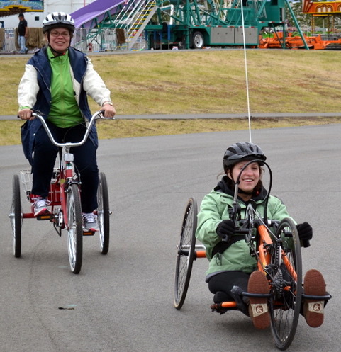 Woman riding a tricycle behind another woman riding a recumbent bicycle
