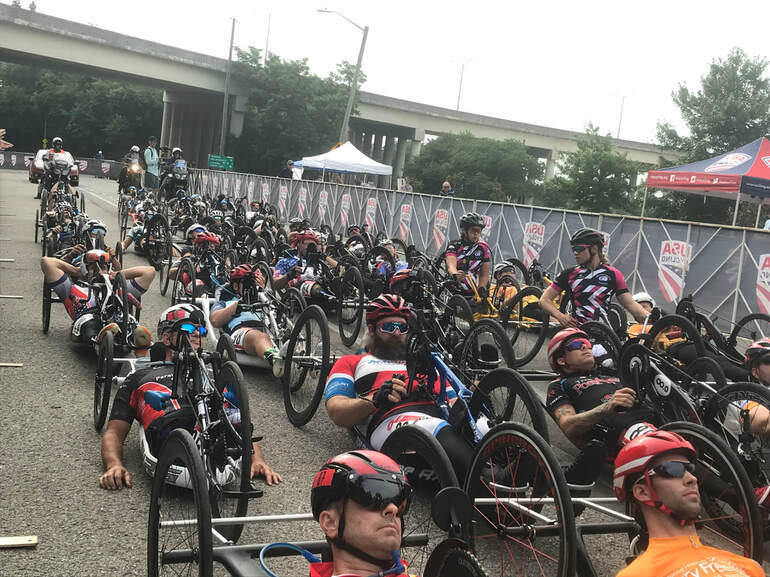 Dozens of recumbent riders lined up on a road to prepare for a ride