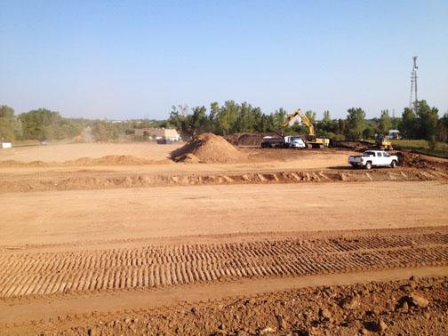 Large dirt lot with white truck on back of lot