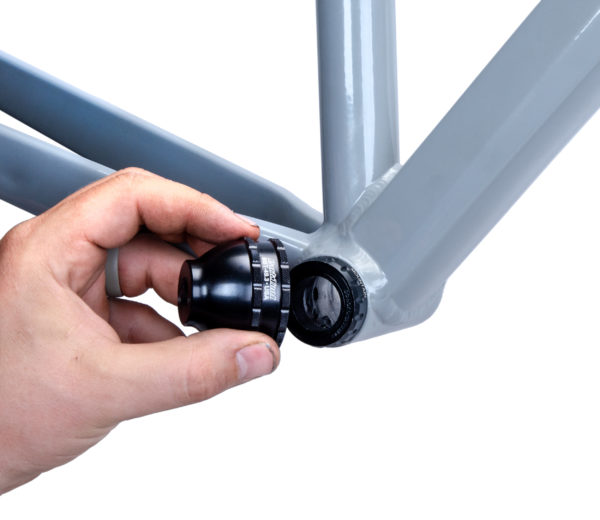 A hand fitting the BBT-49.3 Bottom Bracket Tool onto a black external bottom bracket cup on a gray MTB frame, click to enlarge