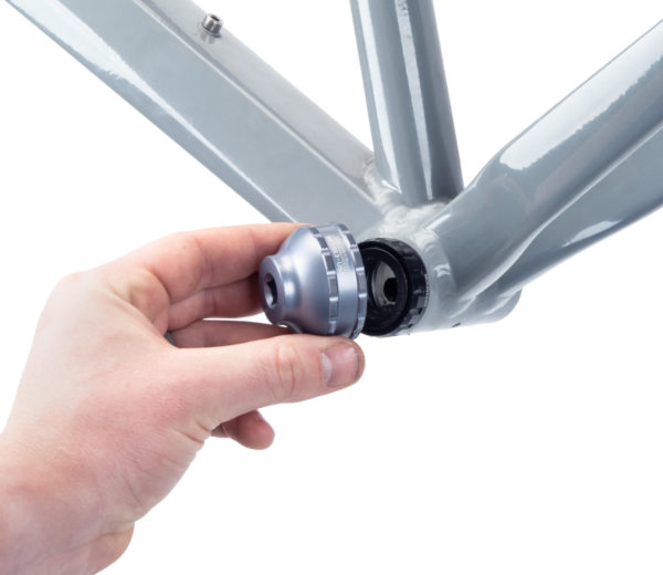 A hand fitting the BBT-59.3 Bottom Bracket Tool onto a black external bottom bracket cup on a gray MTB frame, click to enlarge