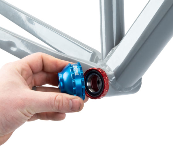 A hand fitting the BBT-69.3 Bottom Bracket Tool onto a red external bottom bracket cup on a gray MTB frame, click to enlarge
