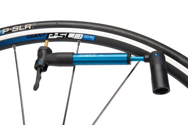 The Park Tool PMP-3.2 Micro Pump in blue secured on Presta valve on road bike wheel with pump handle extended, click to enlarge