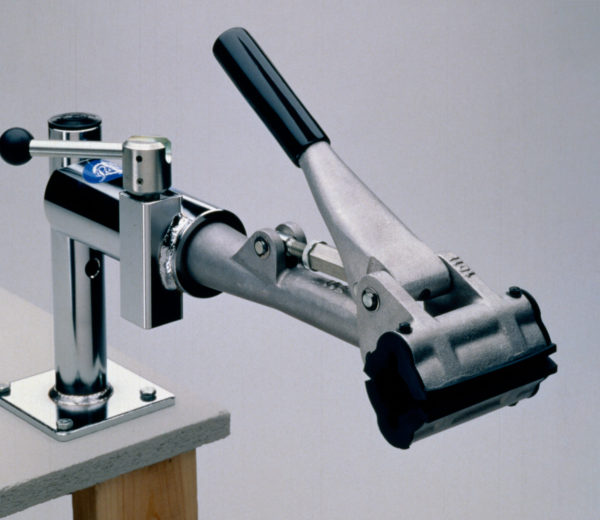The PRS-4 Bench Mount Repair Stand mounted on the corner of an empty workbench, click to enlarge