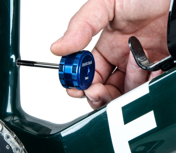 Closeup of a Park Tool TH-3 Tap and Bit Driver driving a TAP-8 Frame Tap on a black bike frame, click to enlarge