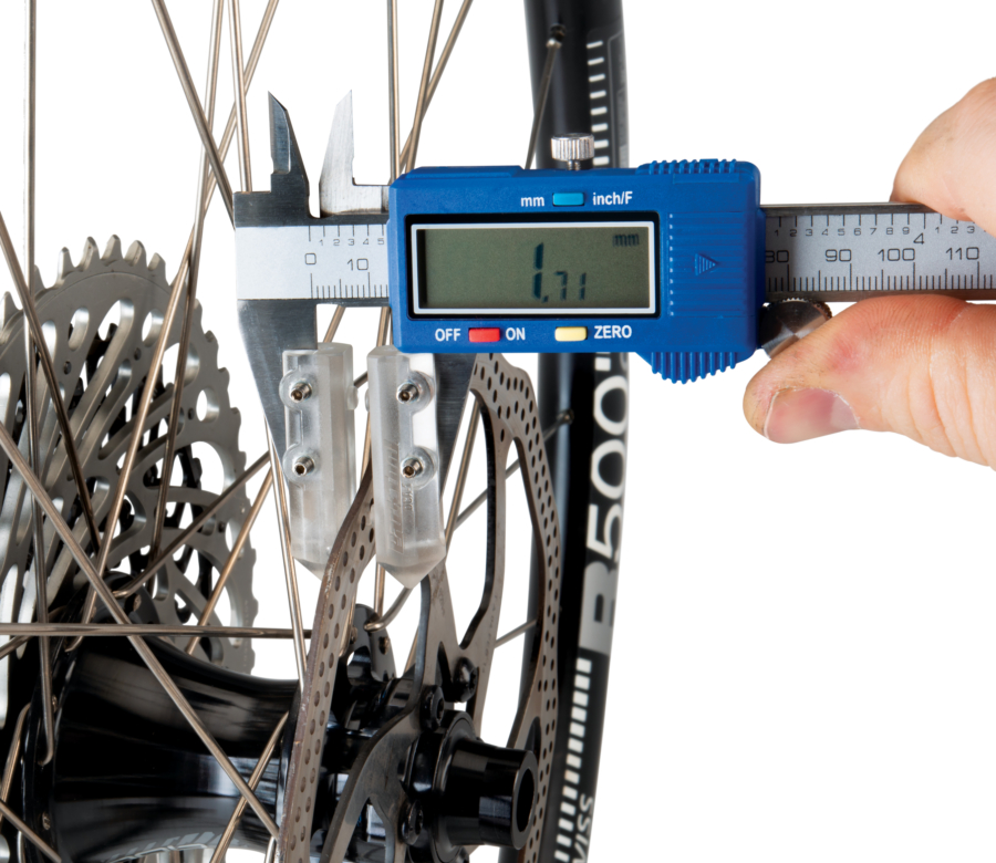 The Park Tool DCA-1 Digital Caliper Accessory measuring thickness of the braking surface on a disc brake, enlarged