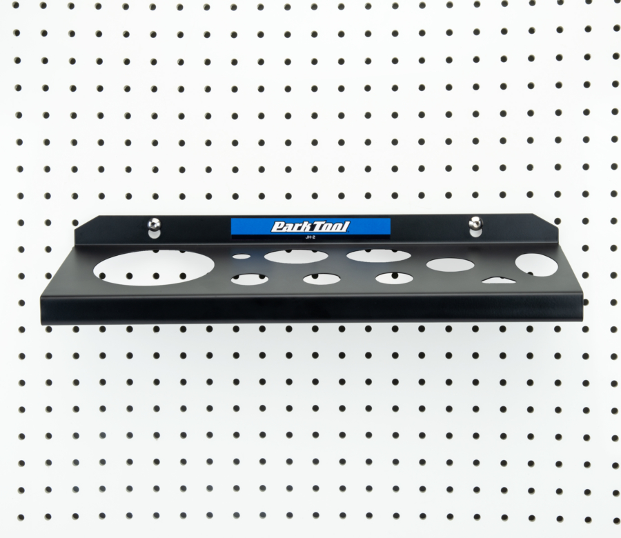 The Park Tool JH-2 Wall-Mounted Lubricant & Compound Organizer mounted to white pegboard, enlarged