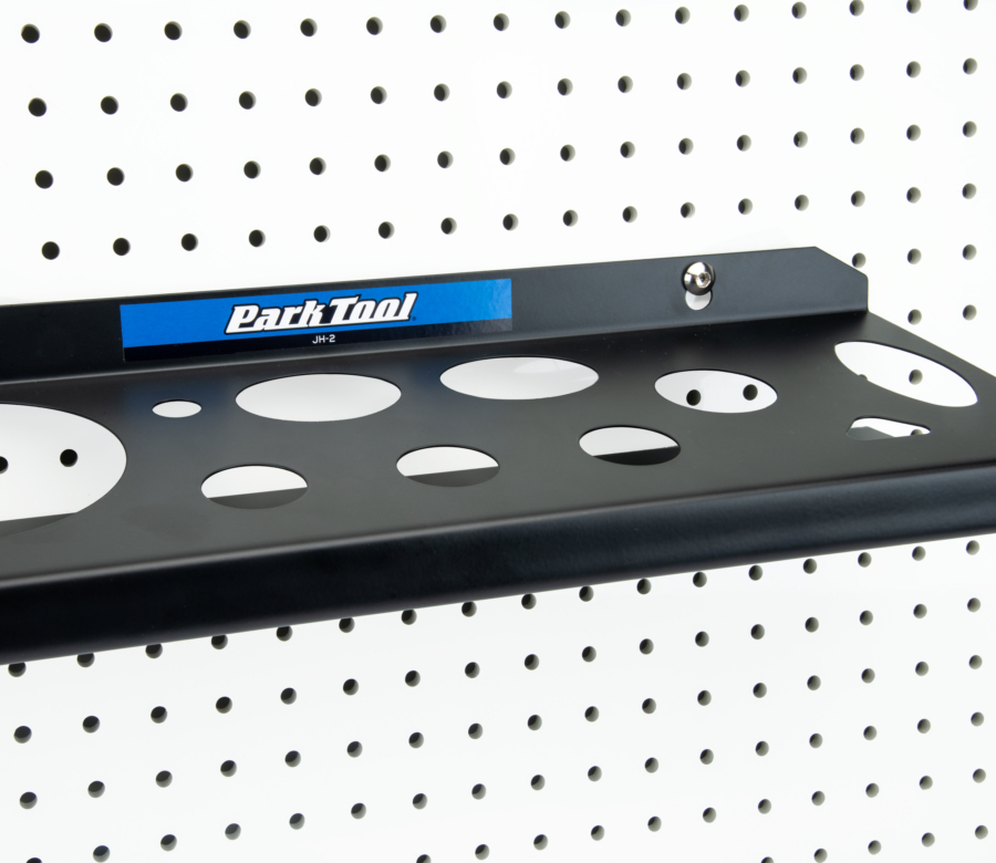 The Park Tool JH-2 Wall-Mounted Lubricant & Compound Organizer mounted to white pegboard, enlarged