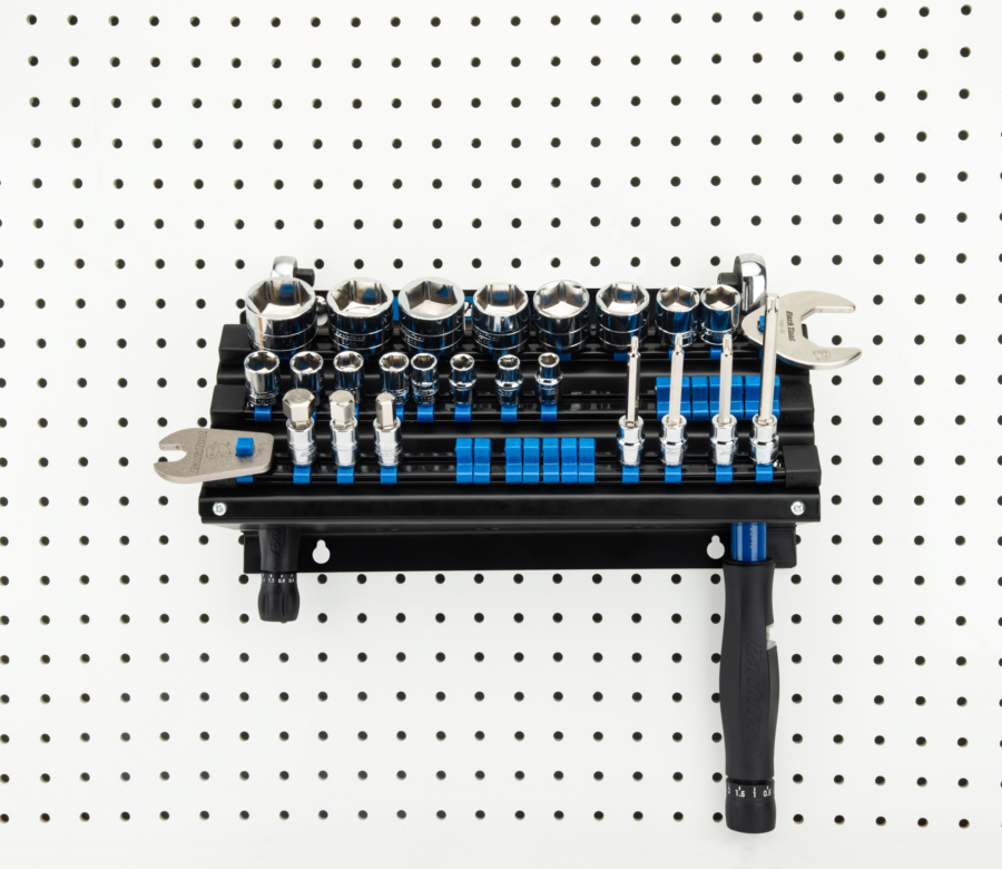 The Park Tool JH-3 Wall-Mounted Socket, Bit & Torque Tool Organizer mounted to white pegboard holding sockets, enlarged