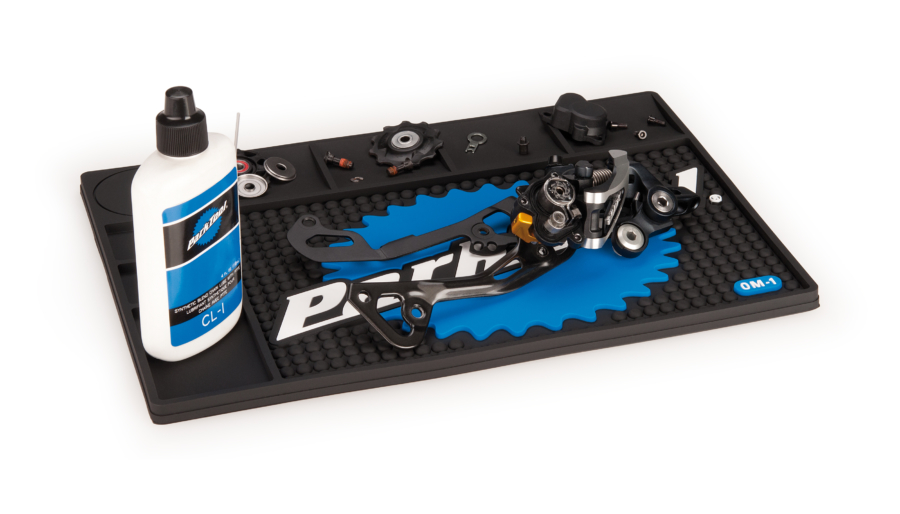 The Park Tool OM-1 Benchtop Overhaul Mat with tools and parts displayed on top, enlarged