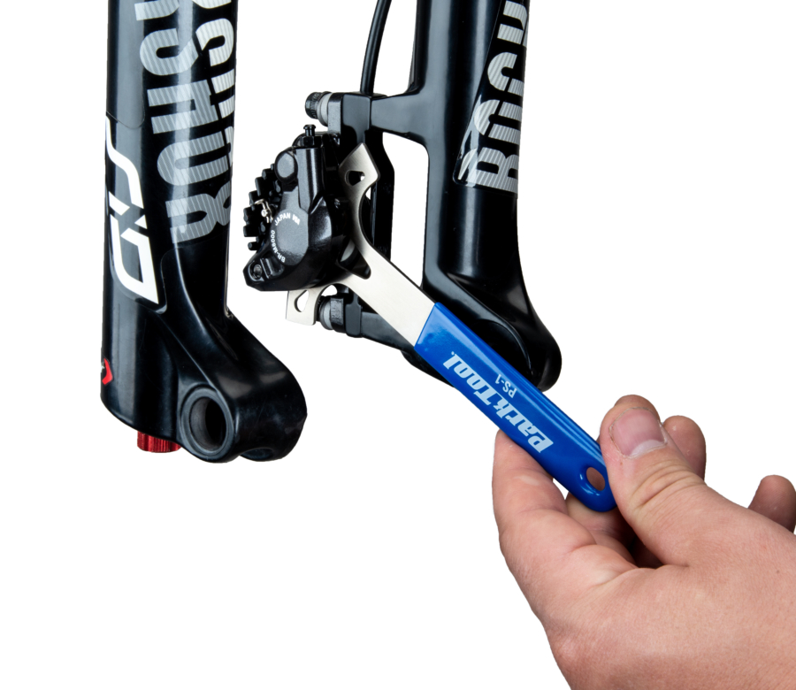 The PS-1 Disc Brake Pad Spreader being inserted into disc brake caliper mounted on a MTB suspension fork, enlarged