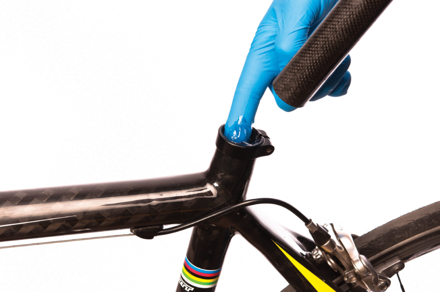 The Park Tool SAC-2 SuperGrip™ Carbon and Alloy Assembly Compound being applied to seat tube using gloved hand, enlarged