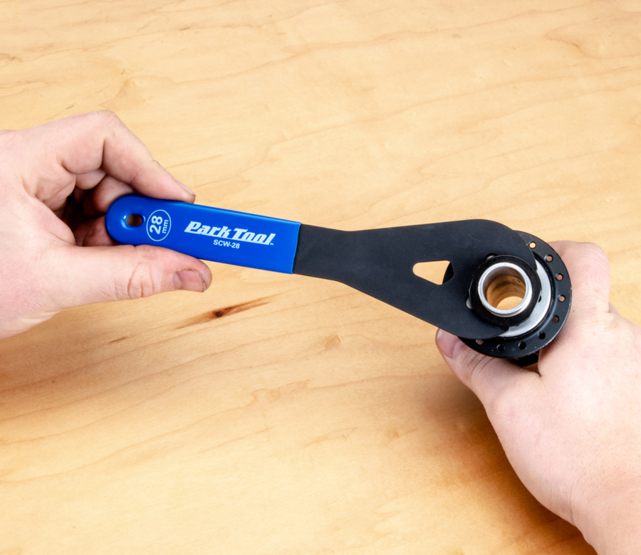 An SCW-28 Cone Wrench being used to adjust a bicycle hub, enlarged