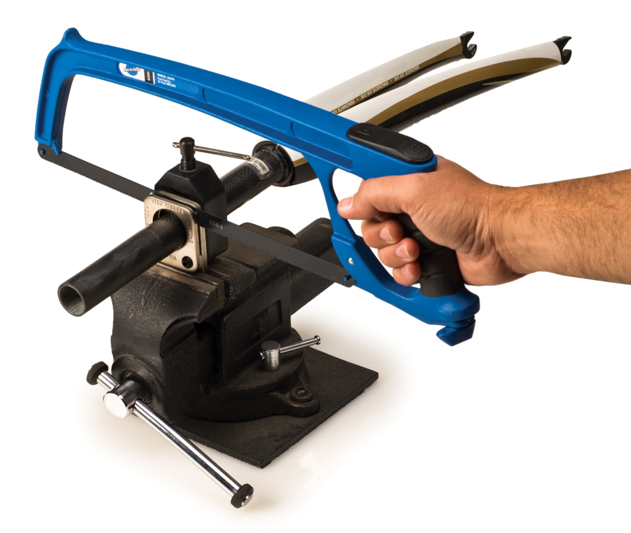 The Park Tool SG-8 saw guide held in vise, holding carbon fiber fork tube while hacksaw with CSB-1 cuts, enlarged