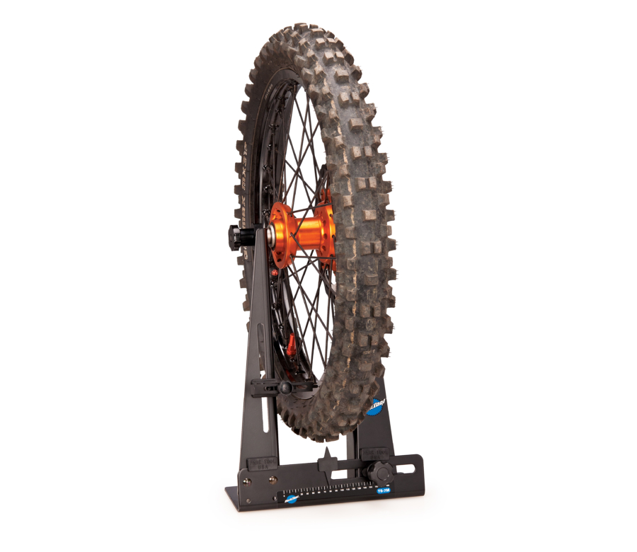 The Park Tool TS-7M Wheel Truing Stand holding a dirt bike wheel with tire, enlarged