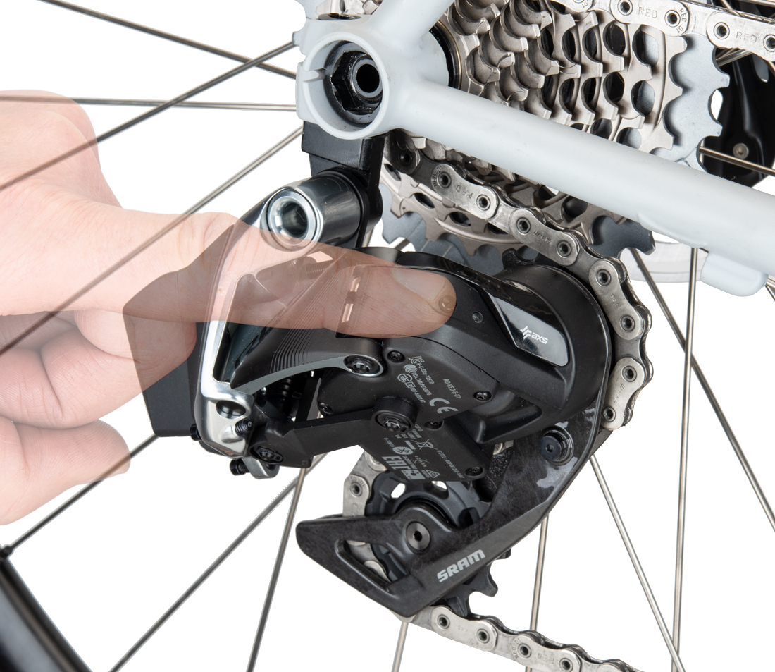 Finger pressing button on rear AXS® derailleur mounted on a bicycle