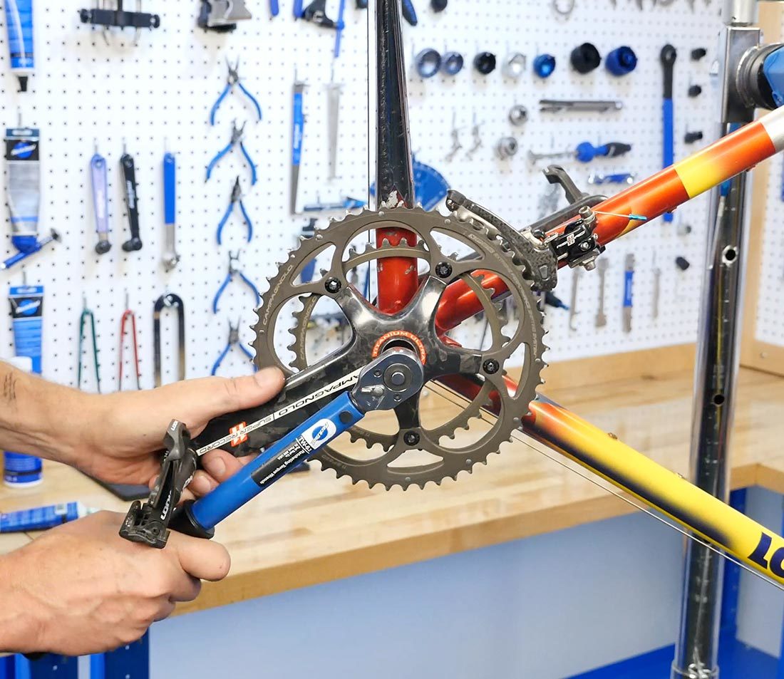 Securing crank bolt with a TW-6.2 torque wrench with hand holding crank arm of bicycle frame in repair stand