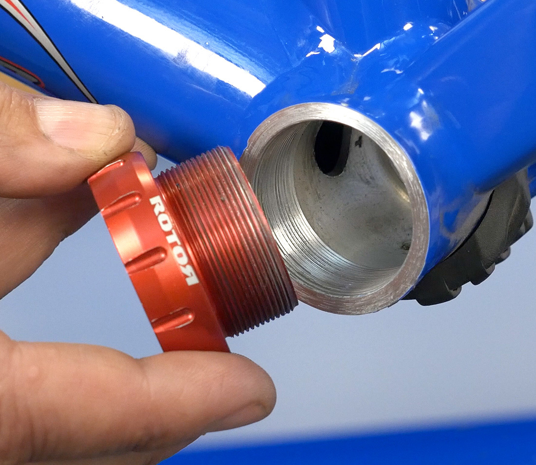 External bottom bracket bearing cup held next to compatible threaded bottom bracket shell