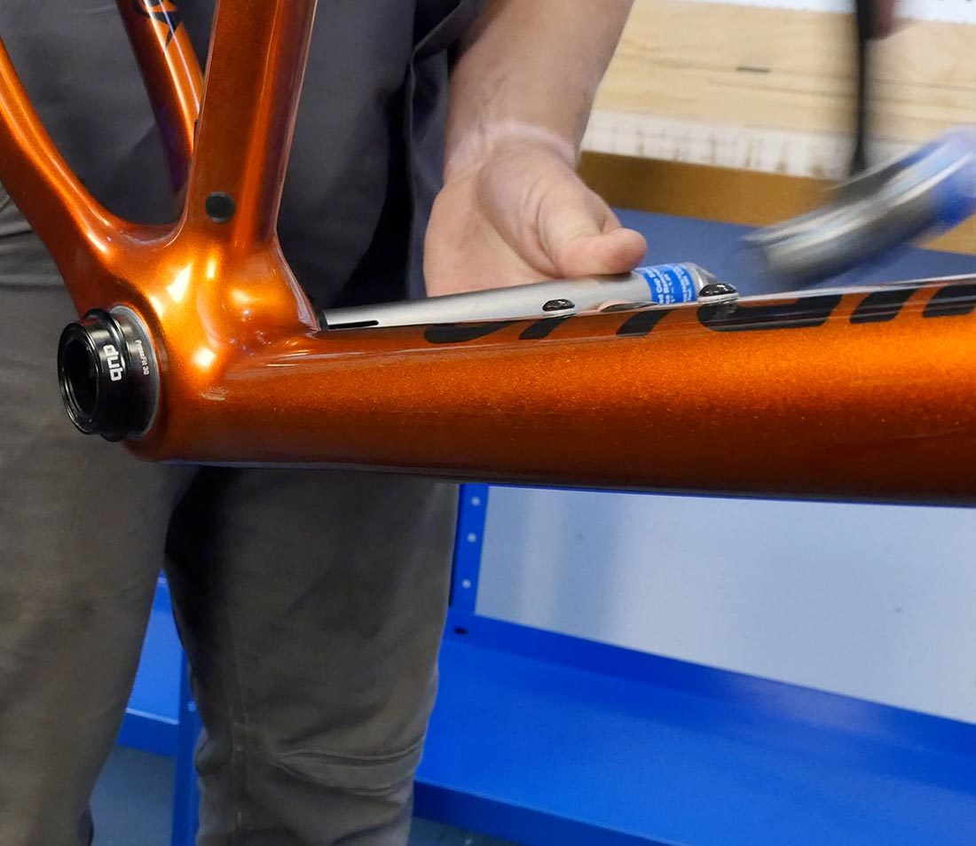 Hammer driving RT-1 installed through bottom bracket shell to remove press fit cup from orange frame
