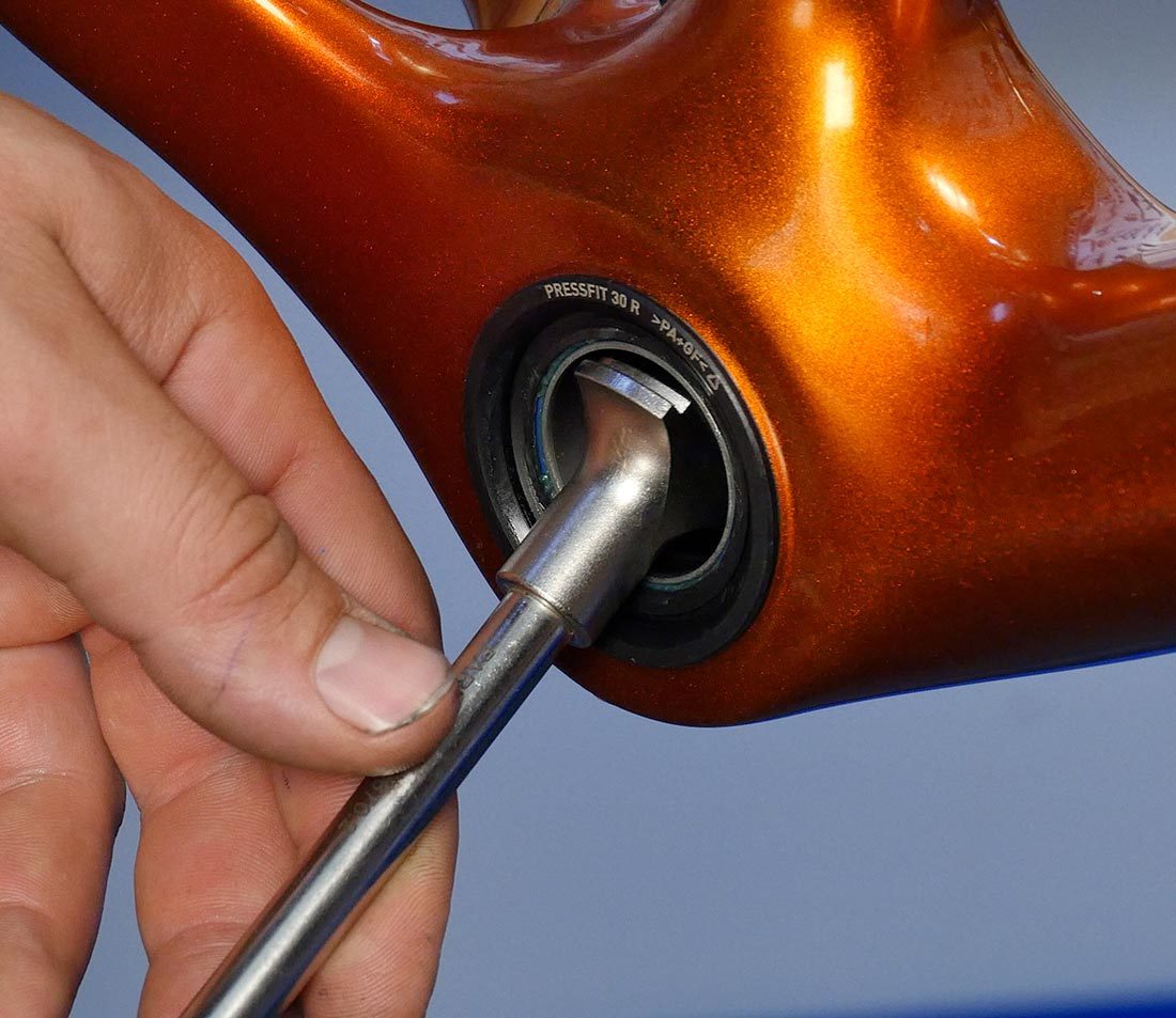 Inserting driving end of BBT-30.4 into press fit bottom bracket cup on orange bicycle frame