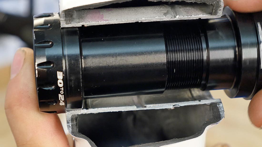 Cutaway section of a press fit bottom bracket shell with thread-together bottom bracket being installed