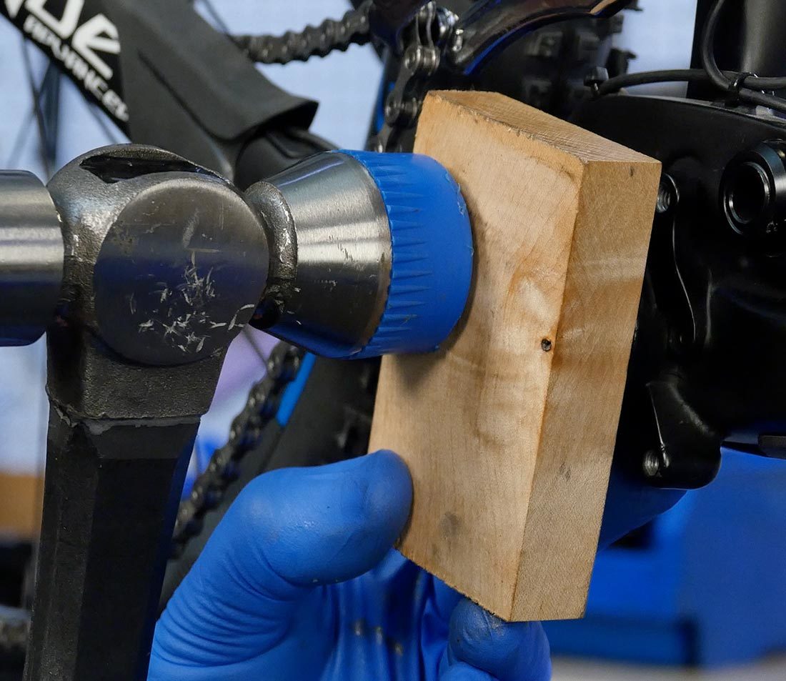 Hammer striking block of wood against partially installed drive side bottom bracket cup