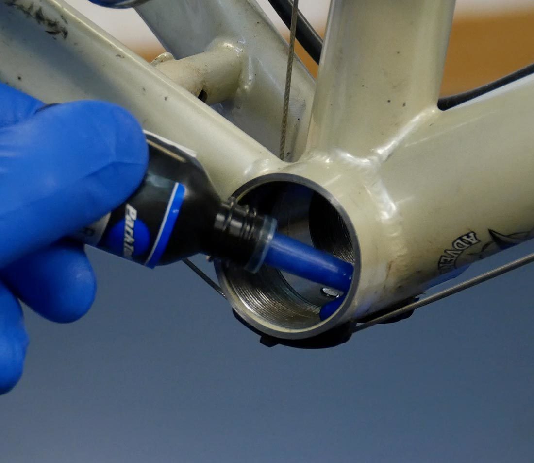 TLR-1 bottle applying threadlocker onto threads of threaded bottom bracket shell on bicycle frame