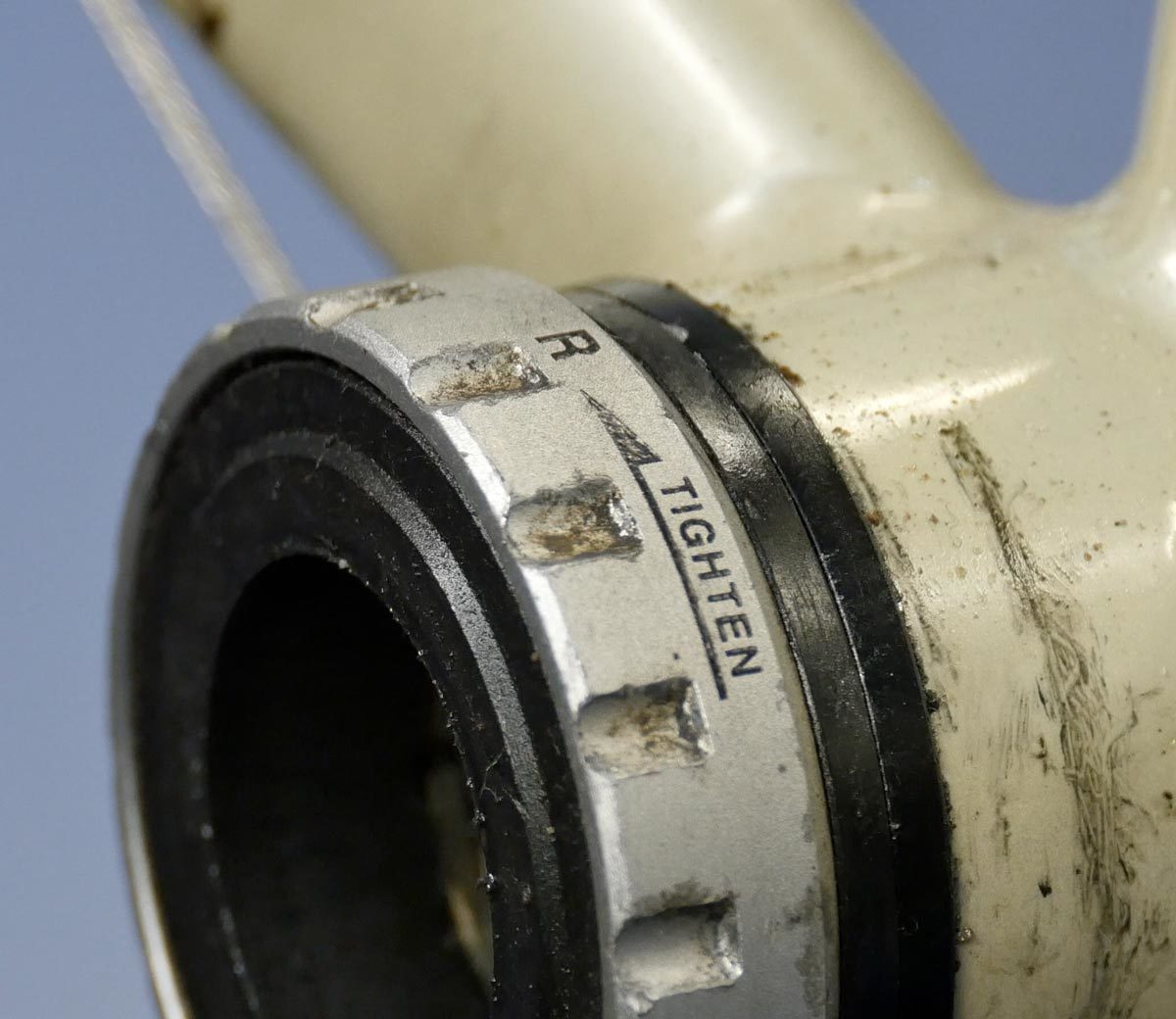 Closeup of external bottom bracket cup on bicycle frame with arrow designating direction of threading