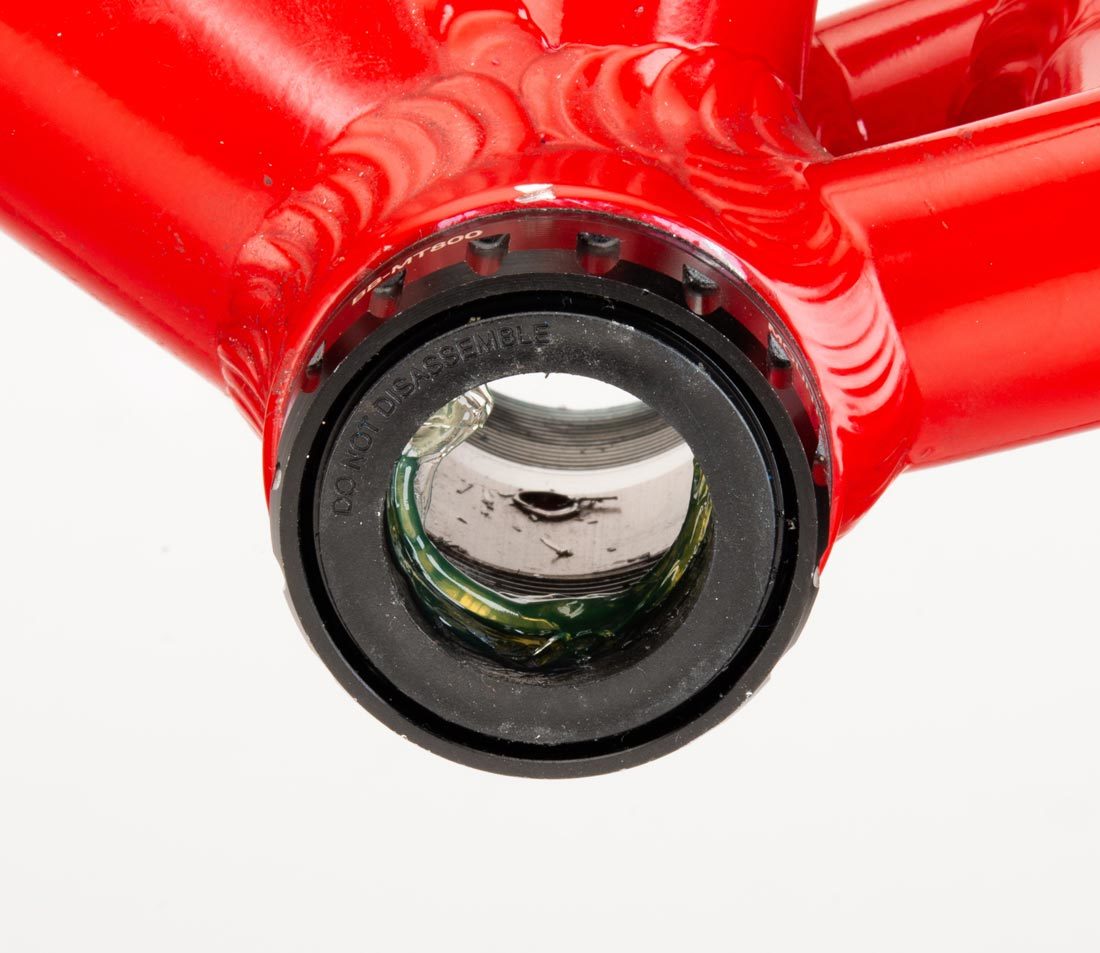 Threaded bottom bracket cup with 16 external notches, installed in bottom bracket shell on red alloy frame