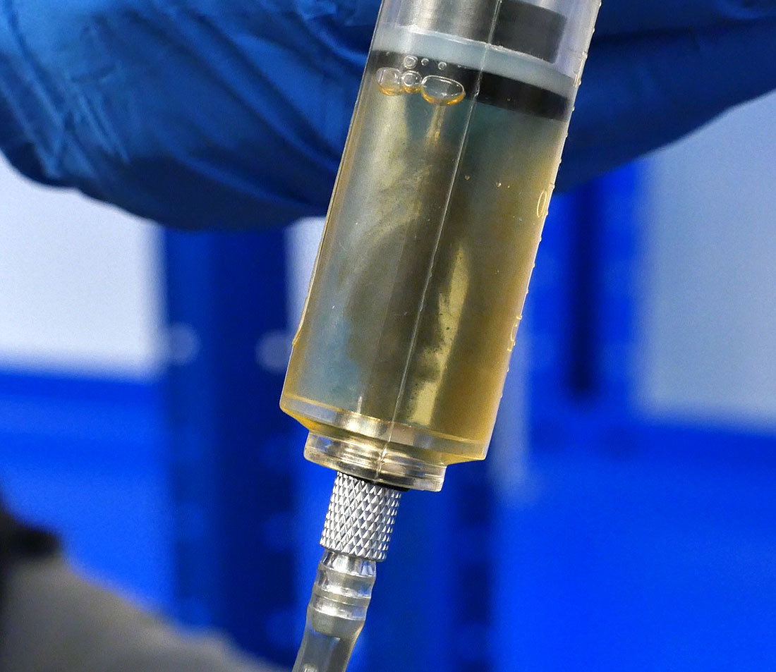Closeup of bleed syringe with dirty fluid entering
