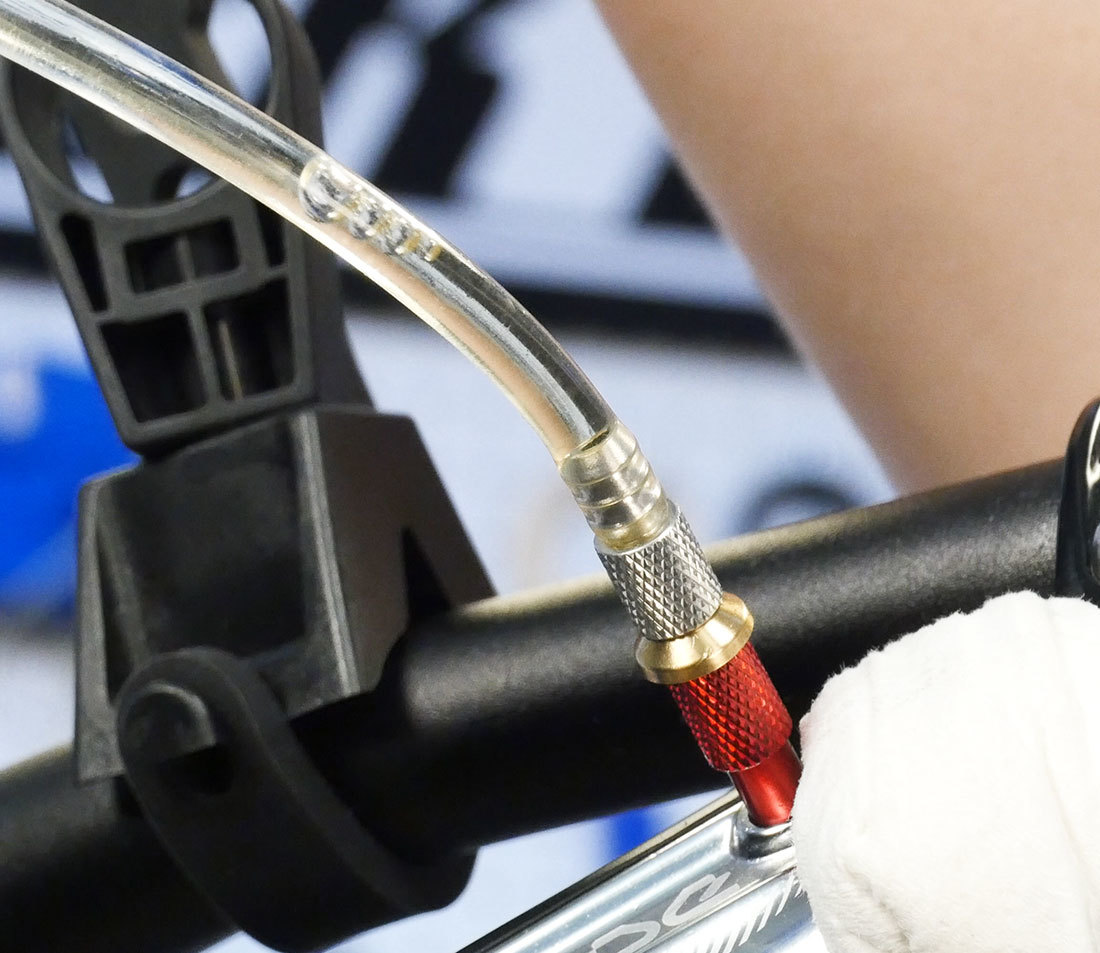 Closeup of air bubbles in syringe hose end at brake lever bleed port