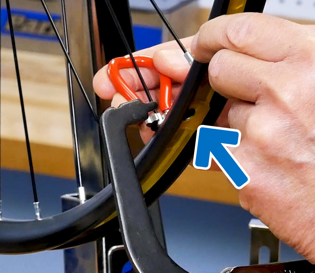Wheel being trued in truing stand, with indicator pointing to the valve hole to use as a reference