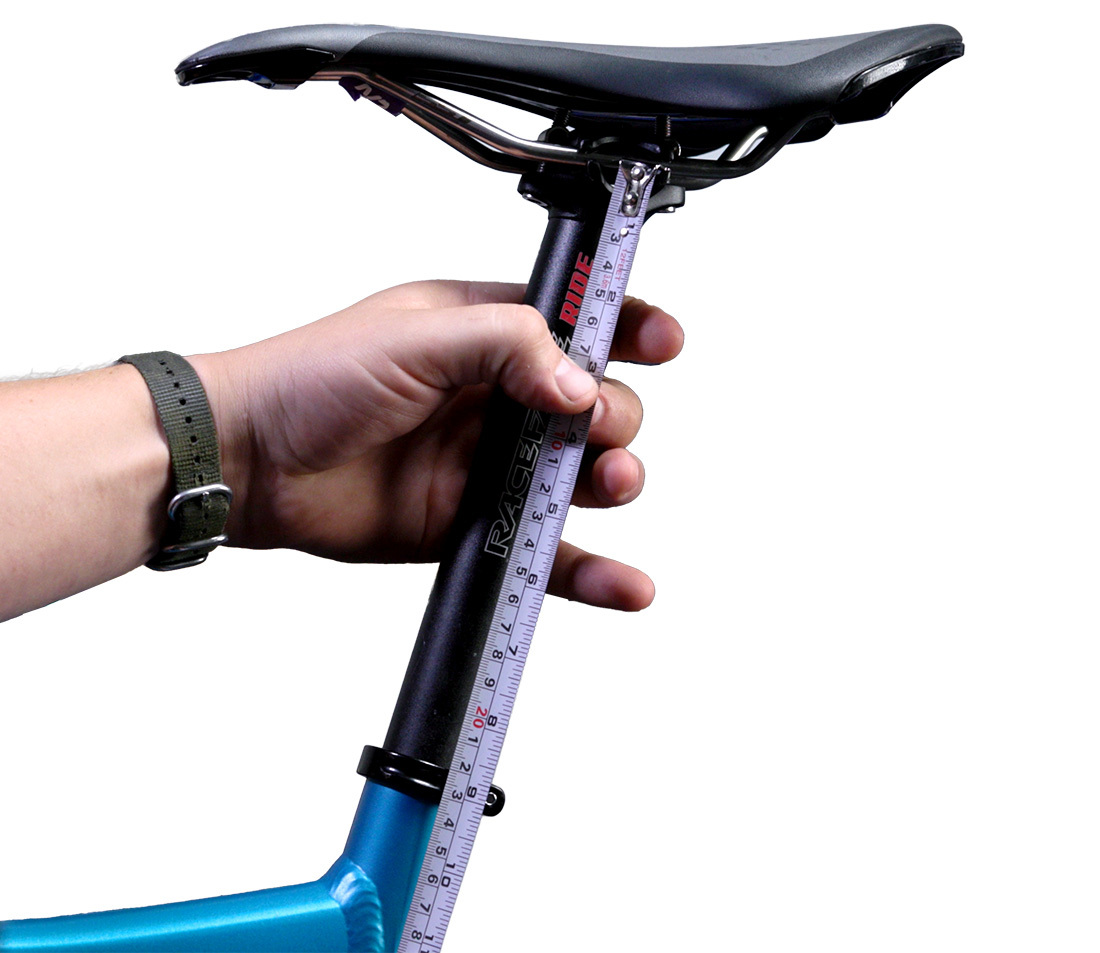 A hand holding a tape measure to a bicycle seatpost, measuring a ride height of 220 mm.