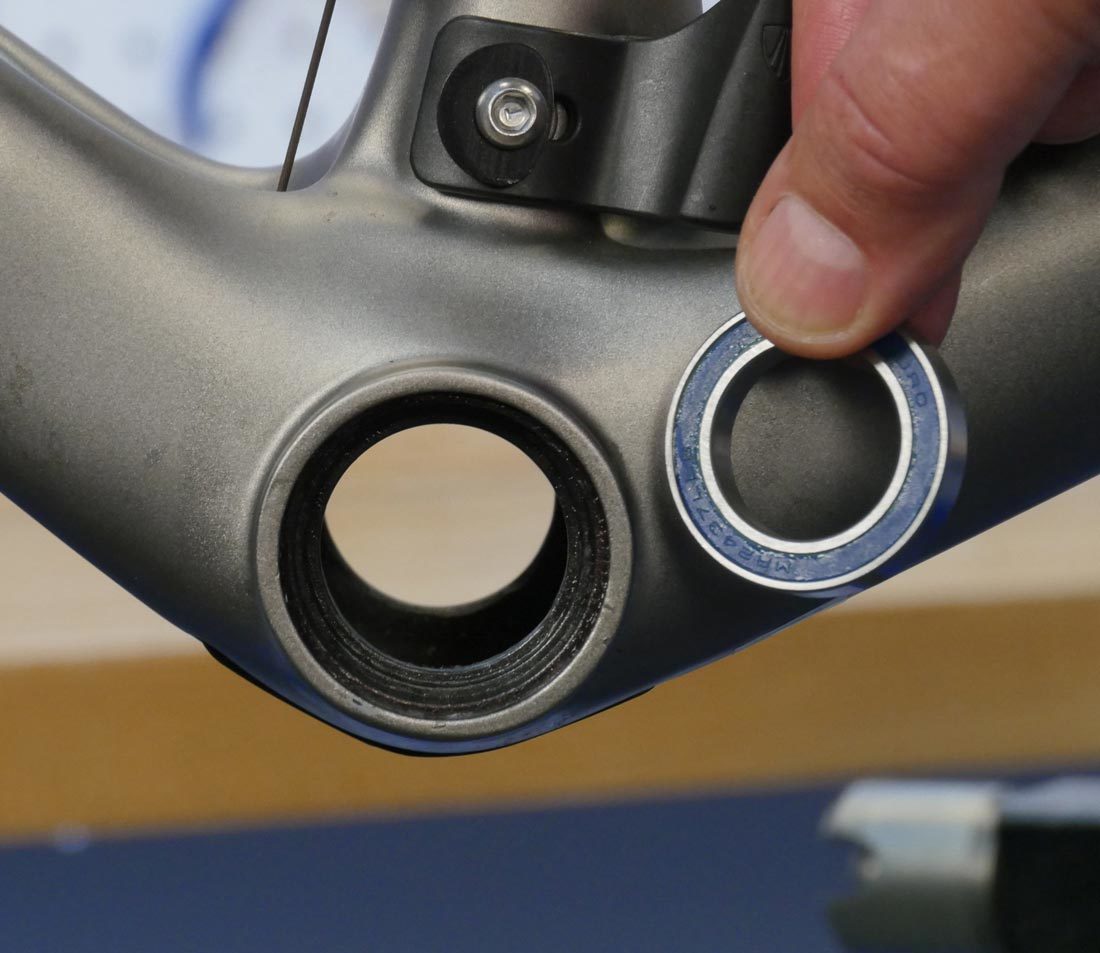 BB90 bearing held next to compatible bottom bracket shell on carbon fiber bicycle frame